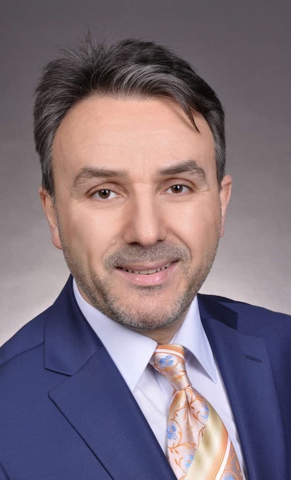 Porträt von Ferruh Aksu im dunkelblauen Anzug mit heller, gemusterter Krawatte